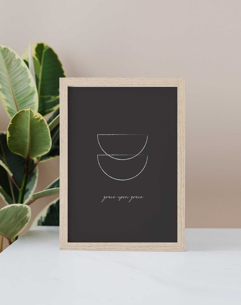 Puede incluir: Una impresi&oacute;n enmarcada con fondo negro y formas geom&eacute;tricas blancas. El texto "grace upon grace" est&aacute; escrito en letras cursivas blancas.
