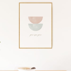 K&ouml;nnte beinhalten: Ein gerahmter Druck mit einem minimalistischen Design, das zwei sich &uuml;berlappende Halbkreise in Rosa- und Blaut&ouml;nen zeigt. Der Text "grace upon grace" ist in einer kursivschriftlichen Schriftart unter den Formen geschrieben.