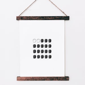 May include: A black and white minimalist art print with a grid of circles. The print is framed in a dark wood frame and hanging on a white wall.