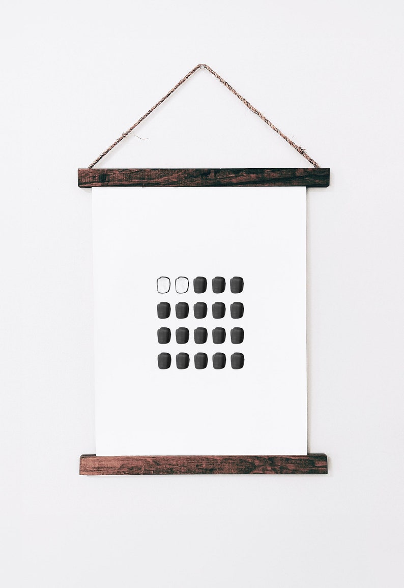 May include: A black and white minimalist art print with a grid of circles. The print is framed in a dark wood frame and hanging on a white wall.