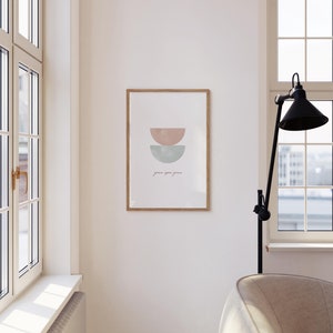 K&ouml;nnte beinhalten: Ein gerahmter Druck mit einem minimalistischen Design, das zwei sich &uuml;berlappende Halbkreise in Rosa- und Blaut&ouml;nen zeigt. Der Text "grace you grow" ist darunter in Kursivschrift geschrieben.