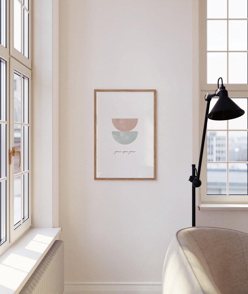 K&ouml;nnte beinhalten: Ein gerahmter Druck mit einem minimalistischen Design, das zwei sich &uuml;berlappende Halbkreise in Rosa- und Blaut&ouml;nen zeigt. Der Text "grace you grow" ist darunter in Kursivschrift geschrieben.