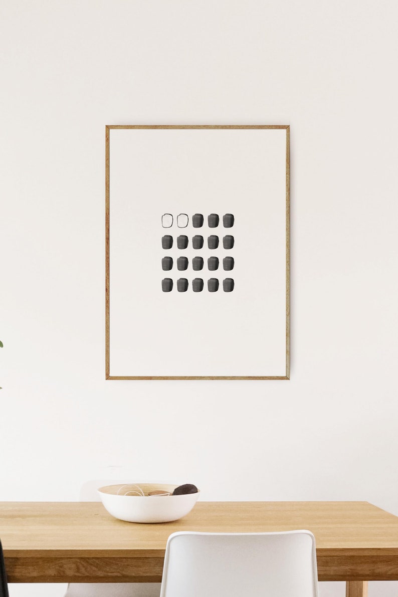 May include: A framed black and white minimalist art print with a grid of 20 small squares. The top row has three squares, the second row has four squares, and the remaining rows have five squares. The squares are filled with black except for the first two squares in the top row, which are white.