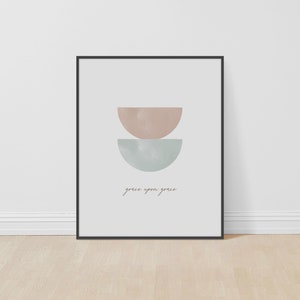 K&ouml;nnte beinhalten: Ein minimalistischer Kunstdruck mit zwei sich &uuml;berlappenden Halbkreisen in Rosa- und Blaut&ouml;nen. Der Text "grace upon grace" ist in einer kursivschriftlichen Schriftart unter den Formen geschrieben.