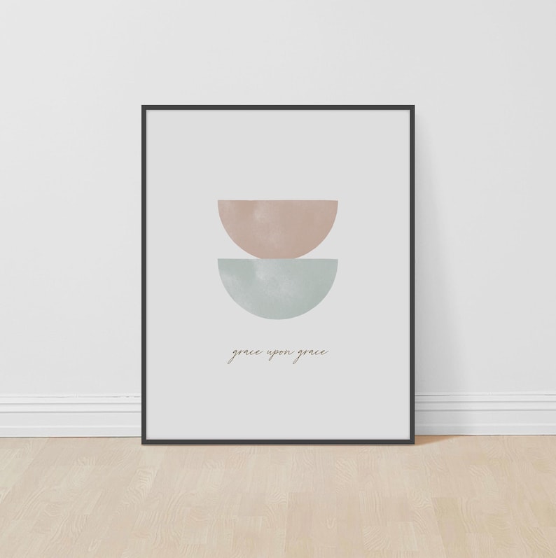 K&ouml;nnte beinhalten: Ein minimalistischer Kunstdruck mit zwei sich &uuml;berlappenden Halbkreisen in Rosa- und Blaut&ouml;nen. Der Text "grace upon grace" ist in einer kursivschriftlichen Schriftart unter den Formen geschrieben.