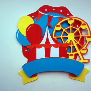 May include: A colorful paper craft set featuring a red and white striped tent, a yellow Ferris wheel, blue and yellow balloons, and a blue banner with a yellow star.