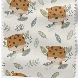Könnte beinhalten: Ein weißer Stoff mit einem sich wiederholenden Muster aus braunen und orangefarbenen gefleckten Leoparden mit rosa Wangen, umgeben von grünen Blättern.