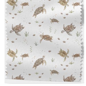Könnte beinhalten: Ein weißer Stoff mit einem sich wiederholenden Muster aus braunen Aquarell-Meeresschildkröten in verschiedenen Größen. Die Schildkröten schwimmen in einem hellblauen Meer mit kleinen weißen Punkten und grünem Seegras.