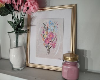 May include: A framed floral painting with pink, blue, and yellow flowers. A clear glass vase with pink flowers and a pink candle in a jar with a gold lid are also present.