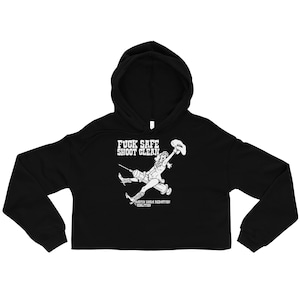 May include: Black cropped hoodie with a white graphic of a cowgirl holding a hat and syringe, with the text "FUCK SAFE SHOOT CLEAN" above the graphic. The hoodie has a drawstring hood and long sleeves.