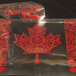 Puede incluir: Calcoman&iacute;a de vinilo rojo de una bandera canadiense con un dise&ntilde;o de mandala. La bandera presenta una gran hoja de arce en el centro y dos dise&ntilde;os de mandala m&aacute;s peque&ntilde;os a cada lado. Las palabras "Canada Day" tambi&eacute;n est&aacute;n incluidas en la imagen.