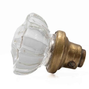 May include: A clear glass door knob with a brass base. The glass is faceted and has a rounded shape.
