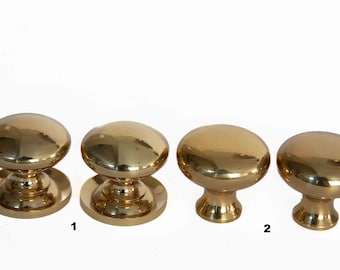 May include: Four polished brass cabinet knobs with a round top and a base. The knobs are arranged in a row from left to right. The numbers "1" and "2" are written below the knobs.