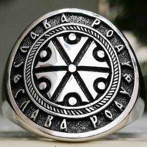 May include: A silver ring with a circular design featuring a five-pointed star with a circle in the center. The ring is inscribed with the words "СЛАВА РОА" in Cyrillic script.