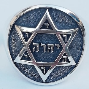 Pode incluir: Um anel de prata com uma Estrela de David de esmalte azul que apresenta a palavra hebraica "דוד" (David) no centro.