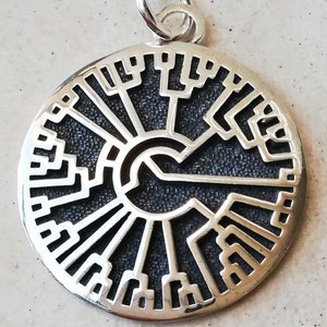 May include: Silver pendant featuring a circular design with a tree of life pattern. The pendant is detailed with a textured black background and a silver outline.