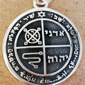 May include: Silver pendant with a black background and Hebrew text. The pendant is divided into four sections, each with a different symbol. The top section features a Star of David. The text around the edge reads "Shem HaMephoreshet".