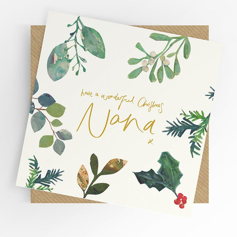 May include: A Christmas card with the message "have a wonderful Christmas Nana" in gold script. The card is decorated with watercolor illustrations of green and brown leaves, holly, and berries. The card is on a brown envelope.