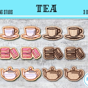 Puede incluir: Nueve diseños de pendientes con forma de taza de té, tetera y macarons. Los diseños están cortados con láser en madera y están disponibles en tres estilos diferentes. El texto "TEA" y "9 SUGS 3 DESIGNS" es visible en la imagen.