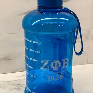May include: A large, transparent blue water bottle with a blue lid and handle. The bottle has the text "ZΦB Finer Women Hydrate 1920" and motivational phrases printed on it. The bottle is designed for hydration.