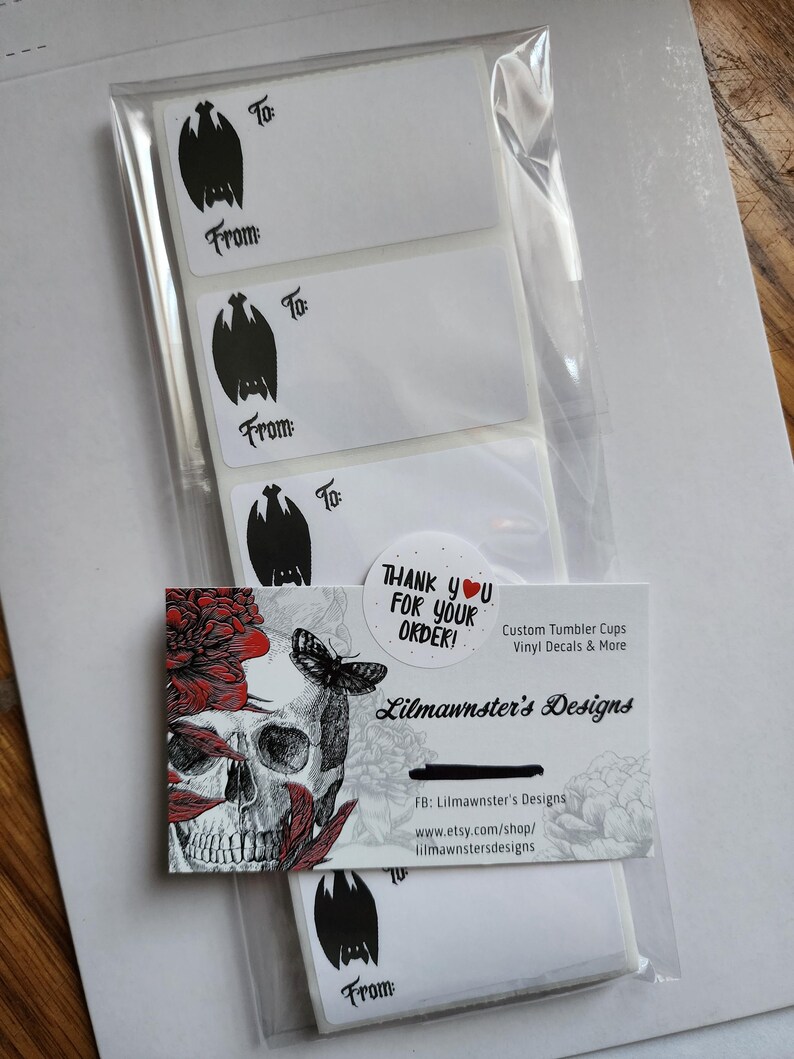 May include: A set of five white gift tags with black bat illustrations and the words "To" and "From". The tags are packaged in a clear plastic bag with a business card that reads "Thank you for your order!" and "Lilmawnster's Designs". The business card also includes the company's social media and website information.