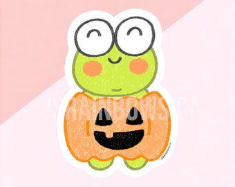 Peut inclure: Une grenouille verte portant un costume de citrouille orange avec un visage de citrouille noire. La grenouille a de grands yeux et un petit sourire.