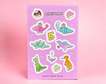 Peut inclure: Une carte rose avec le texte "C'est mon anniversaire !" et le chiffre 5. La carte présente des illustrations de dinosaures portant des chapeaux d'anniversaire et des cadeaux. Le texte "Les dinosaures préférés de Jonathan" est en bas de la carte.