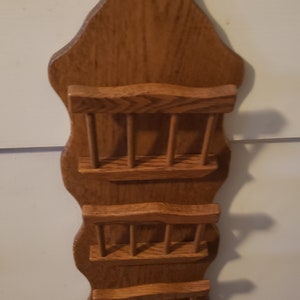 May include: A wooden wall-mounted mail organizer with three compartments and three hooks at the bottom. The organizer is made of light brown wood with a wavy design.
