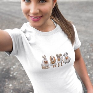 Puede incluir: Camiseta blanca con un gr&aacute;fico de cuatro perros disfrazados de fantasmas para Halloween. Los perros llevan s&aacute;banas blancas con agujeros para los ojos y llevan cubos de calabaza.