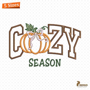 May include: An embroidered design featuring the words "COZY SEASON" in brown and green, with an orange pumpkin and a pink bow. The design is available in 5 sizes. The image is on a white background.