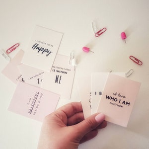 May include: Pink and white affirmation cards with positive messages such as "I choose to be happy", "I am beautiful inside and out", and "I love who I am right now".