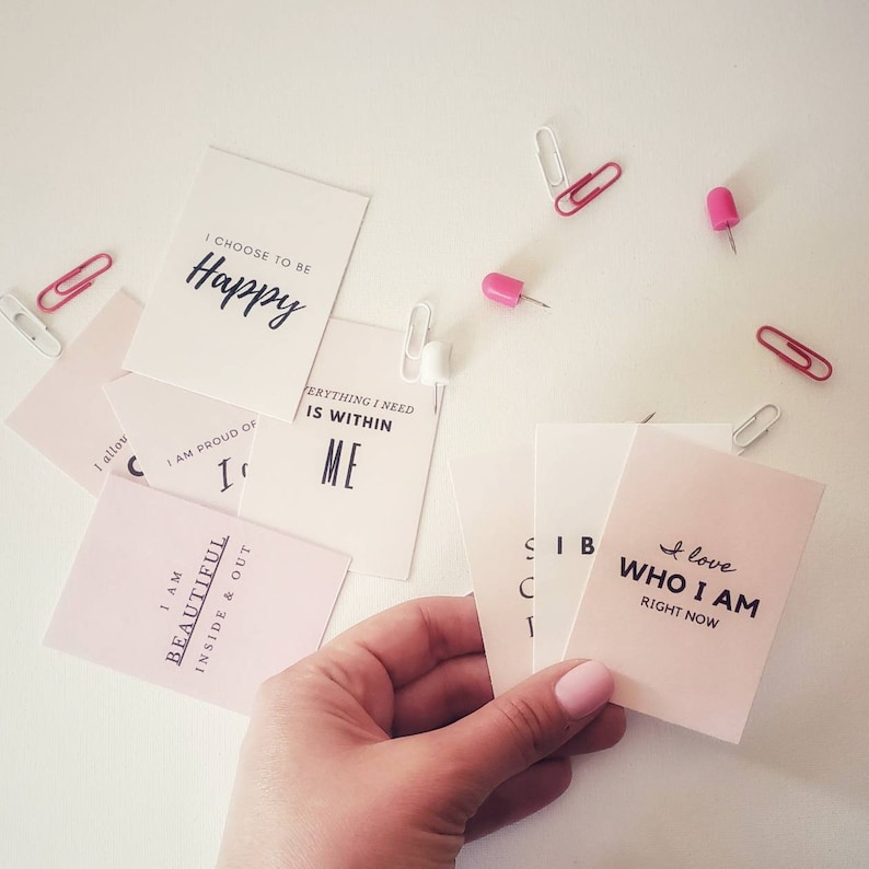 May include: Pink and white affirmation cards with positive messages such as "I choose to be happy", "I am beautiful inside and out", and "I love who I am right now".