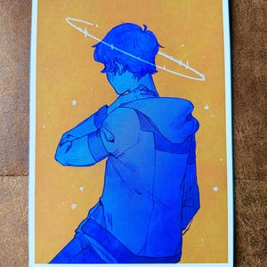 May include: A blue illustration of a person in a hoodie, facing away from the viewer, with a halo-like design above their head. The background is a gradient of yellow and orange with small white stars. The artwork is framed with a white border.