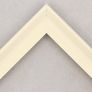 May include: A close-up of a corner of a white picture frame. The frame is made of wood and has a smooth finish.
