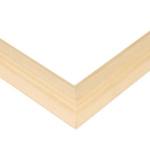 May include: Close-up of the corner of a natural wood picture frame. The frame is made of unfinished, light-colored wood with a smooth surface.