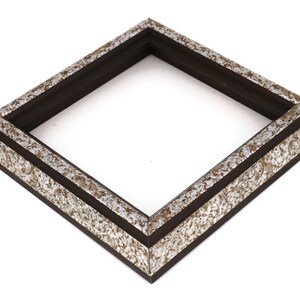 May include: A square picture frame with a black wood frame and a silver and brown metallic finish.