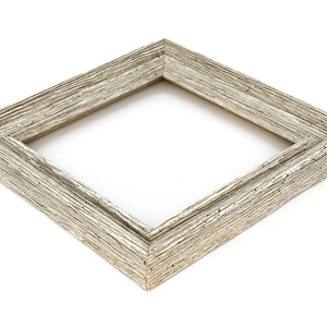 May include: A silver picture frame with a textured wood-like finish. The frame is square and has a simple design.