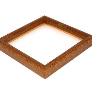 May include: A simple, wooden picture frame with a light brown finish. The frame is made of solid wood and has a slightly distressed look.