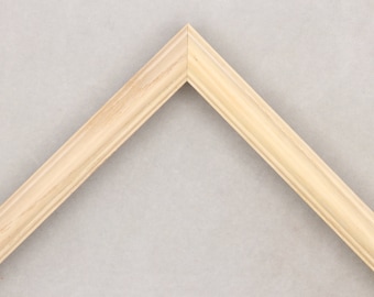 May include: A close-up of a natural wood picture frame with a simple, slightly rounded profile.
