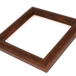May include: A dark brown wooden picture frame with a square opening. The frame has a simple, classic design.