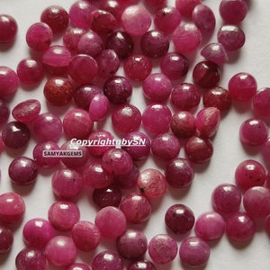 Puede incluir: Una colección de piedras preciosas de rubí redondas y rojas. Los rubíes son de varios tamaños y tienen un acabado liso y pulido. Copyright by SN SAMYAKGEMS