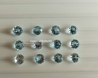 May include: Twelve round, faceted, light blue gemstones arranged in three rows of four on a white surface.  Copyright by SN SAMYAKGEMS.