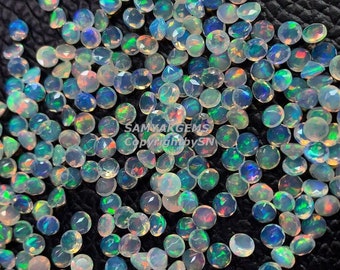 Pode incluir: Uma coleção de pedras preciosas de opala iridescente soltas em uma variedade de formas e tamanhos. As opalas são uma mistura de branco, azul, verde e amarelo.