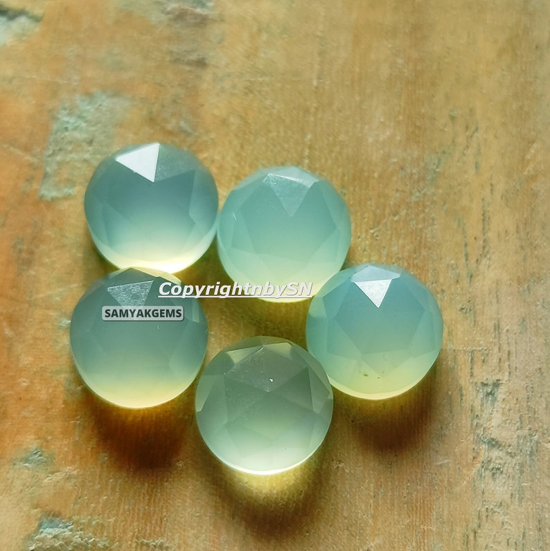 May include: Five faceted, light green gemstone cabochons. The cabochons are round and have a smooth, polished surface.