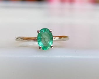 May include: A silver ring with a green oval emerald gemstone.
