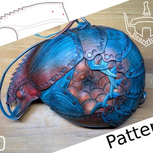 May include: A handcrafted, blue and red leather object with a unique, scaled design. The object has a rounded shape with intricate details, including rivets and embossed patterns. The word "Pattern" is visible in the image.