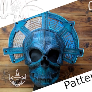 Könnte beinhalten: Eine detaillierte, blaue Totenkopfmaske mit aufwendigen Designs und Text, die eine haloartige Struktur aufweist. Die Maske befindet sich vor einem Holzgrund, mit einem Muster und dem Wort "Pattern" sichtbar.