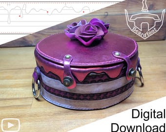 May include: A round, metallic magenta leather box with a lid featuring three sculpted leather roses. The sides have a layered, cake-like design with embossed patterns, secured by two metallic straps with studs and silver-toned side rings.