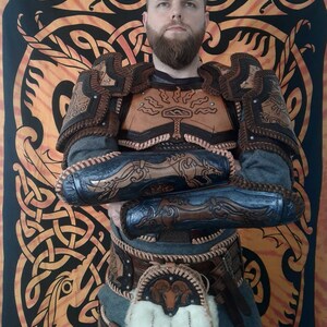 May include: A person wearing a brown leather armor with intricate designs. The armor includes a chest piece, shoulder pads, and arm guards. The person is also wearing a brown leather belt with a pouch and a white fur trim.