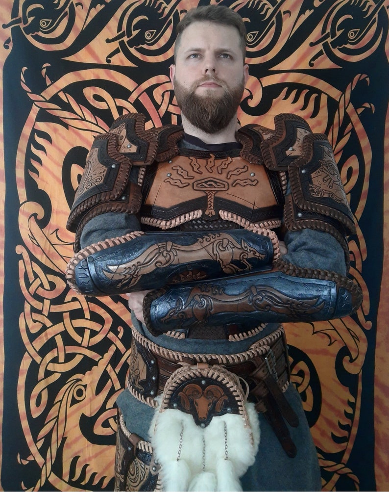 May include: A person wearing a brown leather armor with intricate designs. The armor includes a chest piece, shoulder pads, and arm guards. The person is also wearing a brown leather belt with a pouch and a white fur trim.